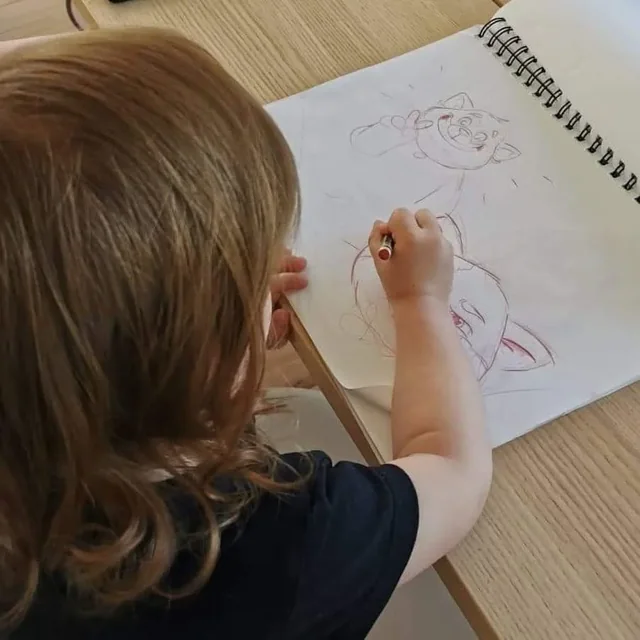 Une fillette colorie un croquis de Laura dans un carnet