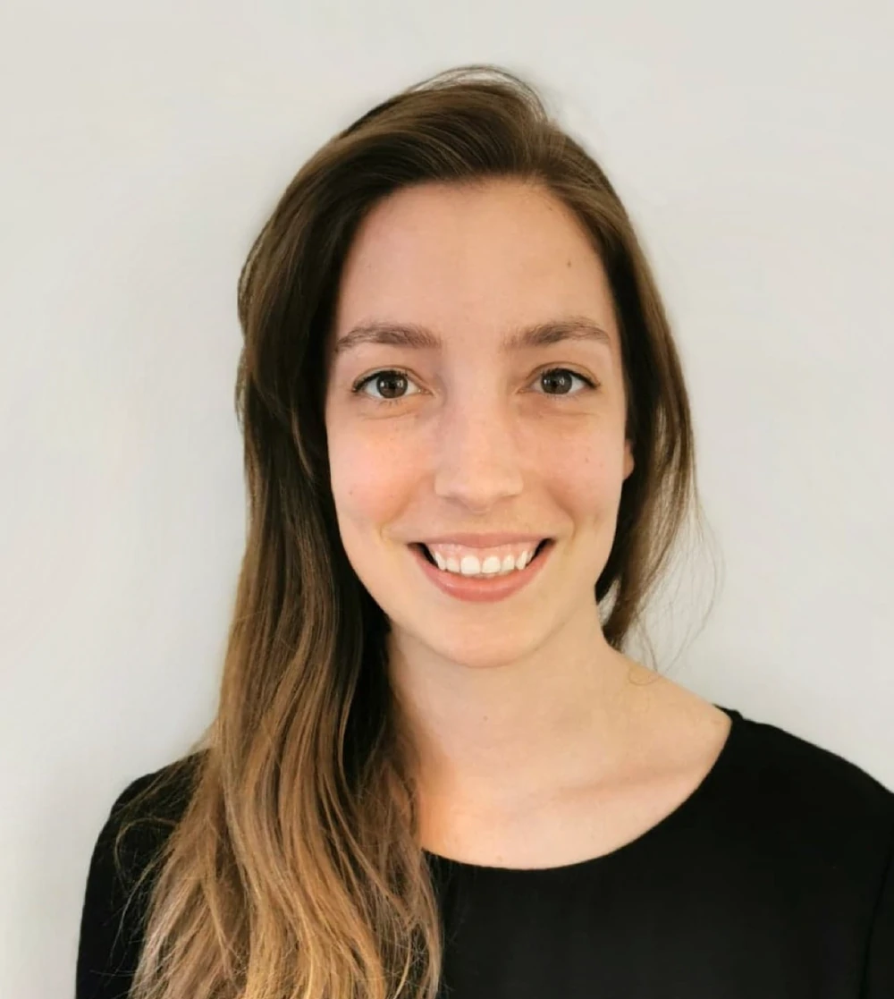 Photo de Laura Vandal, souriante, devant un mur gris