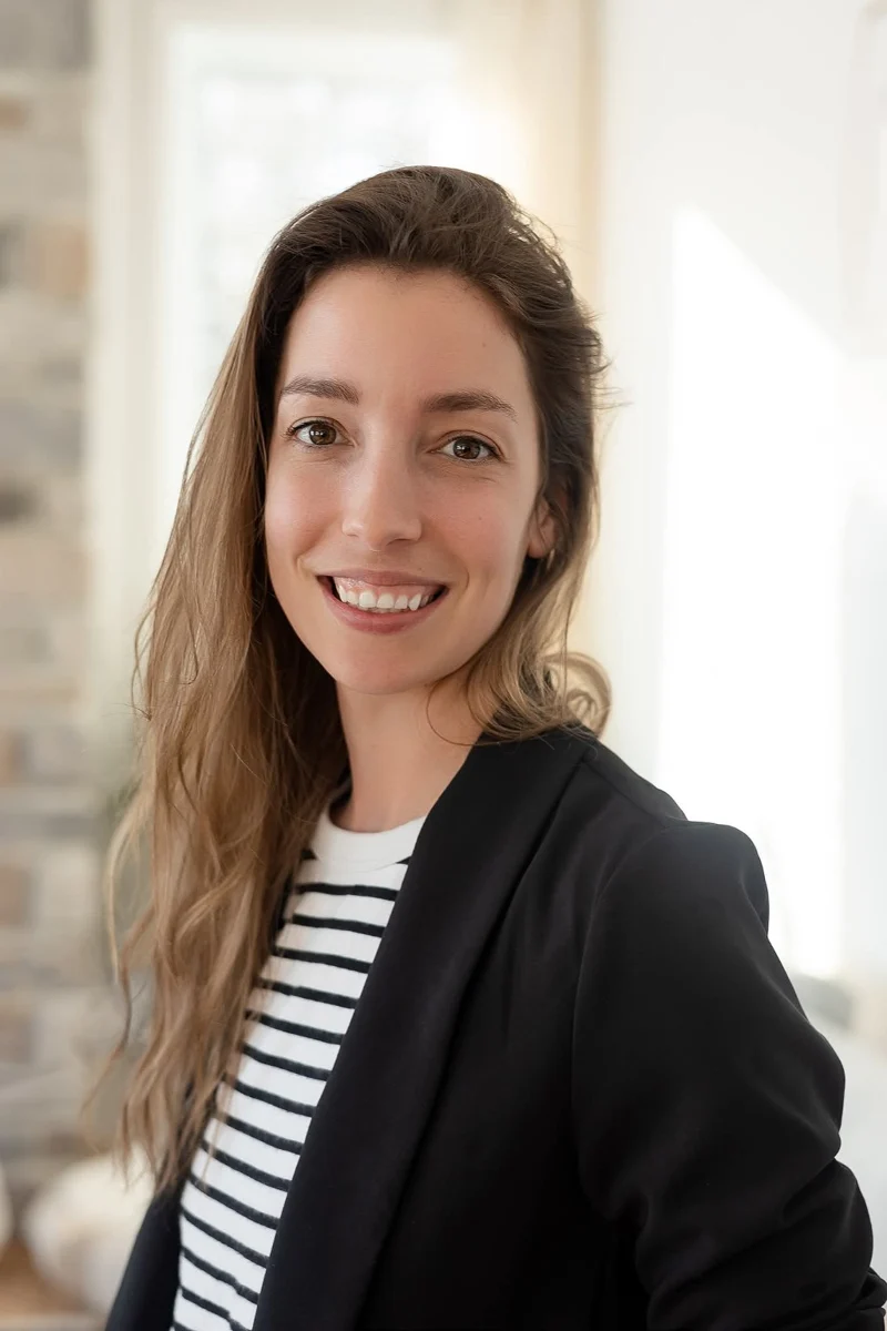 Laura Vandal sourit, en blazer noir et chandail rayé